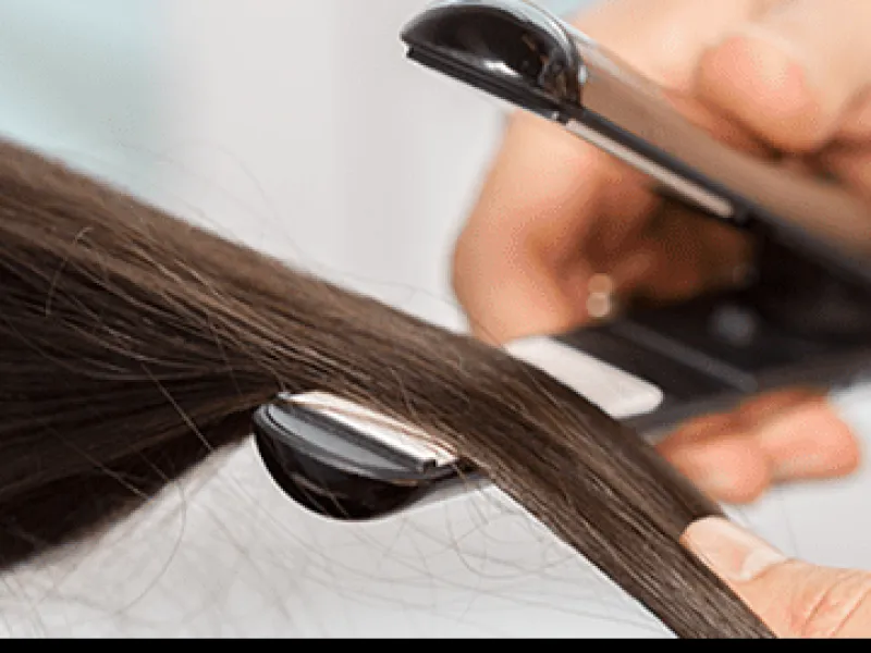 Profissional passando a prancha numa mecha fina de cabelo castanho